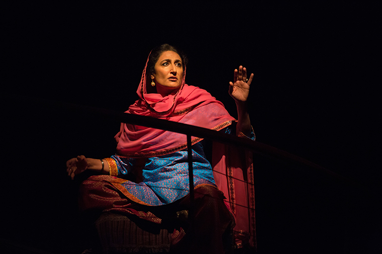 This image shows one woman wearing blue and pink. All around her is black.
