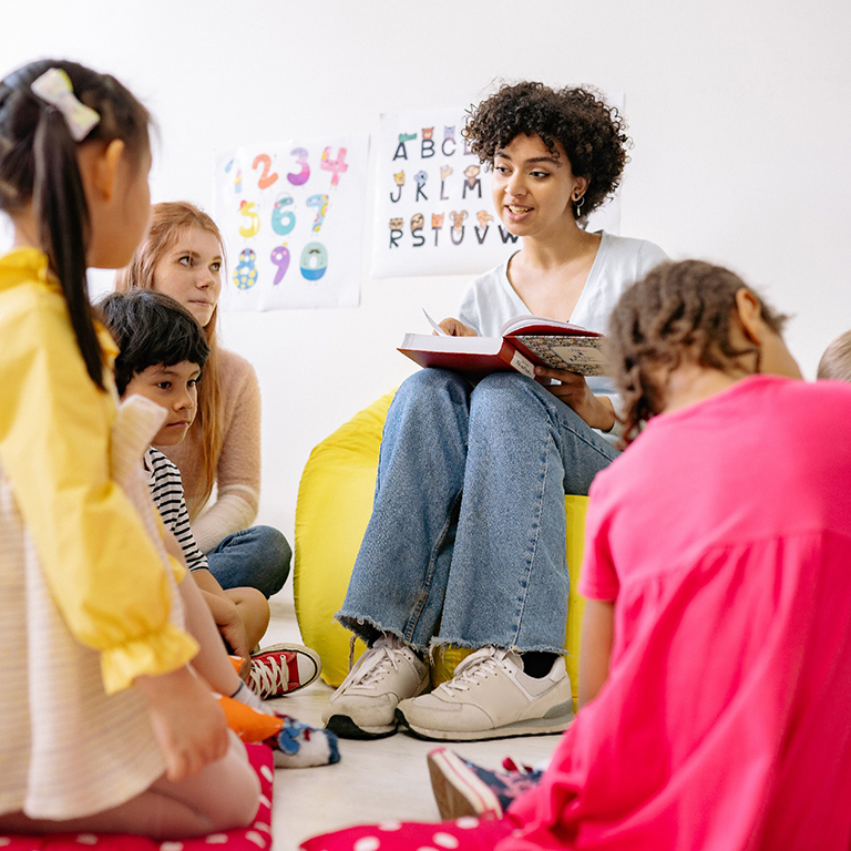 Photo of teaching showing a book to her students.